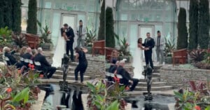 A bride and groom kiss at their indoor wedding ceremony by a pond. A photographer loses balance and falls into the water, causing guests to react in surprise.