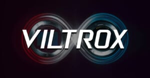 The image features the word "VILTROX" in bold white letters over two camera lens mounts arranged in an infinity symbol, with red and blue light effects on a dark background.
