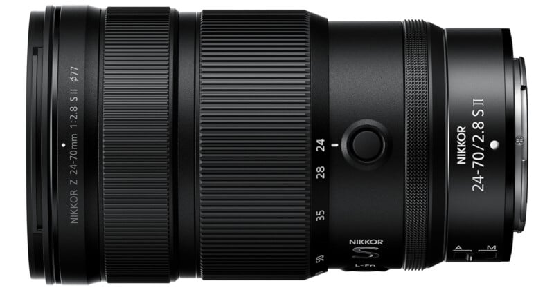 A close-up side view of a NIKKOR Z 24-70mm f/2.8 S II camera lens, showing detailed markings and textured zoom and focus rings, with the lens in a horizontal position.