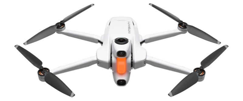 A white quadcopter drone with four black propellers, a front-facing camera, and an orange accent below the camera, shown against a plain white background.