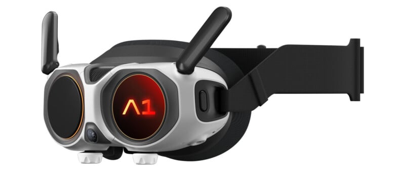 A pair of futuristic VR goggles with two black antennas, a black adjustable head strap, and a glowing red "A1" symbol on the left lens. The device has a sleek, modern white and black design.