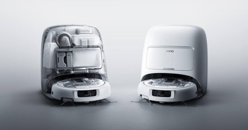 Two white robotic vacuum cleaners are shown side by side; one has its top open to reveal internal components and storage, while the other is closed, both set against a plain light background.