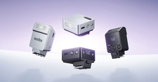 Four compact Godox camera flash units are floating against a gradient purple and white background, showcasing their different angles, buttons, and digital displays.