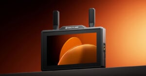 A portable Hollyland monitor with two antennas displays an abstract orange and yellow graphic on its screen, set against an orange gradient background.