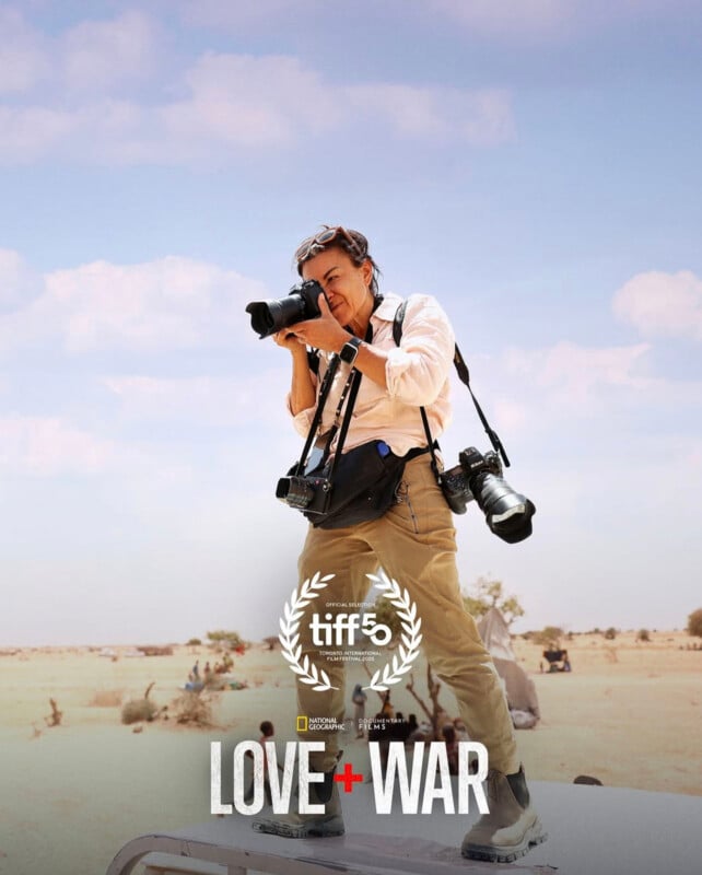 A photographer stands on a vehicle in a desert landscape, holding a camera and looking through the viewfinder. Two more cameras hang from their shoulders. Text reads: "tiff 5 LOVE + WAR," with film festival and sponsor logos.