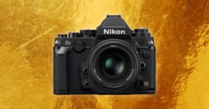 A black Nikon Df DSLR camera with a lens is centered against a textured gold background.
