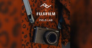 A Fujifilm X-E4 camera with a blue strap hangs against a brown, leopard-print fabric background. The text above reads "FUJIFILM FIELD LAB" with a geometric logo.