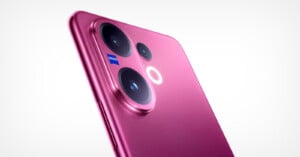 Close-up of a pink smartphone’s rear camera module featuring three lenses and a small Zeiss logo, against a plain white background.
