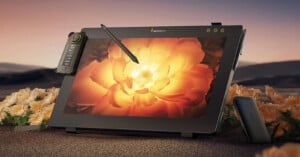 A digital drawing tablet with a stylus displays a vivid yellow flower on its screen. The device is surrounded by matching real flowers and set against a soft, warm background.