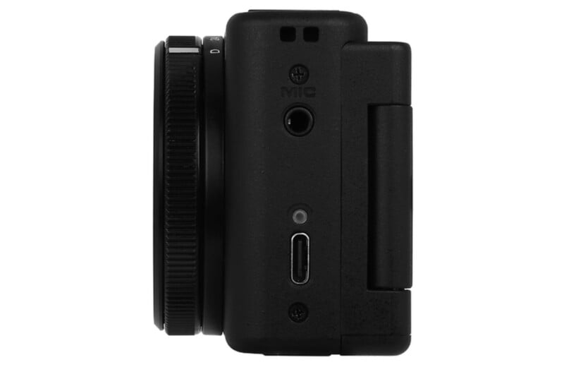 Side view of a black digital camera showing a lens, a MIC port, a USB-C port, and a hinged cover.