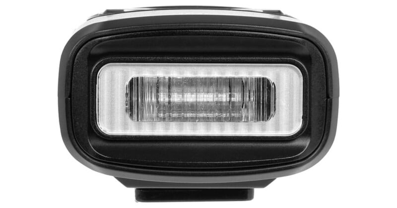 Close-up of a rectangular bicycle headlight with a central LED strip, surrounded by a black casing. The light has a modern, compact design and is photographed against a white background.
