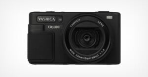 A black Yashica City300 digital camera with a large lens, textured grip, and labeled buttons, shown facing forward against a plain white background.