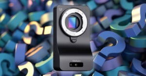 A black YoloCam S7 camera body with no lens is shown in front of a colorful background filled with overlapping 3D question marks in blue, purple, and green tones.