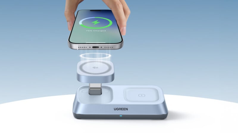A hand holds a smartphone showing 75% charged above a silver UGREEN wireless charging station with multiple charging pads, including elevated charging zones and a USB-C connector.