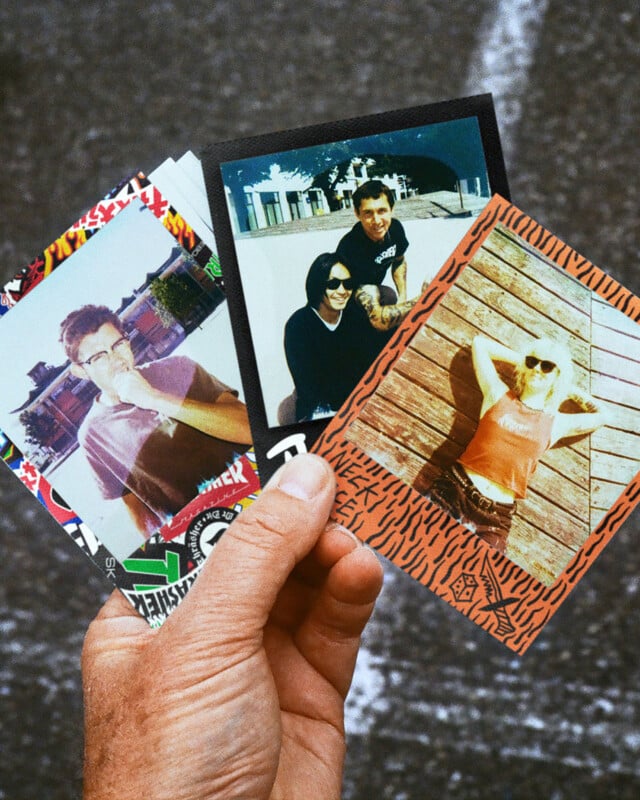 A hand holds three colorful, decorated instant photos showing different people posing outside in sunny locations, with buildings and wooden planks visible in the backgrounds.