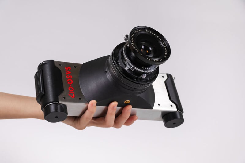 Mano sosteniendo una cámara moderna única con lente ancha y "SO-012" Escrito con lados rojos en un fondo puro.