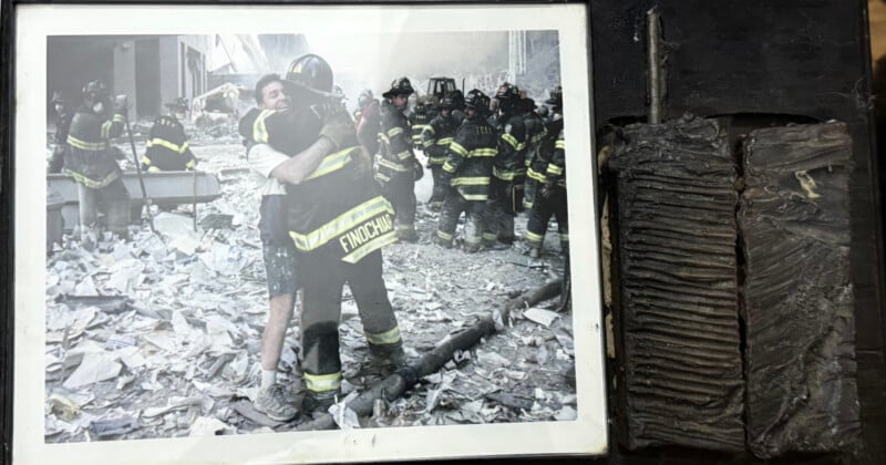 A framed photo shows two men—one in firefighting gear—embracing amid debris, while several firefighters stand behind them. To the right of the photo is a charred, ribbed metal object.