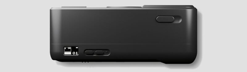 A black electronic device viewed from the bottom, showing an on/off switch, three small buttons, and a larger rectangular button, all set against a plain light gray background.