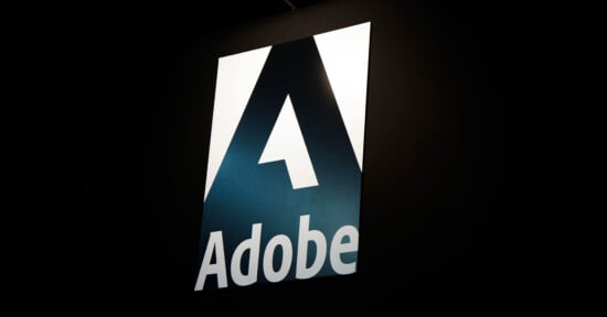 The image shows the Adobe logo, featuring a large stylized white "A" on a dark background with the word "Adobe" written below it in bold white letters.