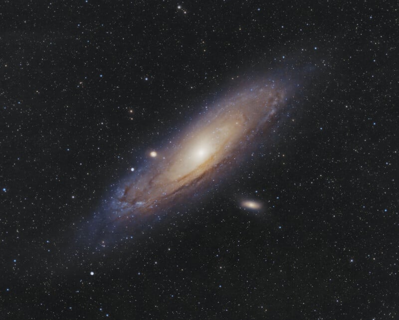 A spiral galaxy, glowing with a bright core and swirling arms, is surrounded by countless stars and smaller galaxies against the black backdrop of space.
