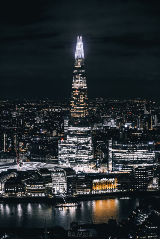 Night Cityscape, con rascacielos fragmentados en Londres, iluminado y reflejado en el río Thames, rodeado de varias luces y edificios de la ciudad bajo cielos oscuros.