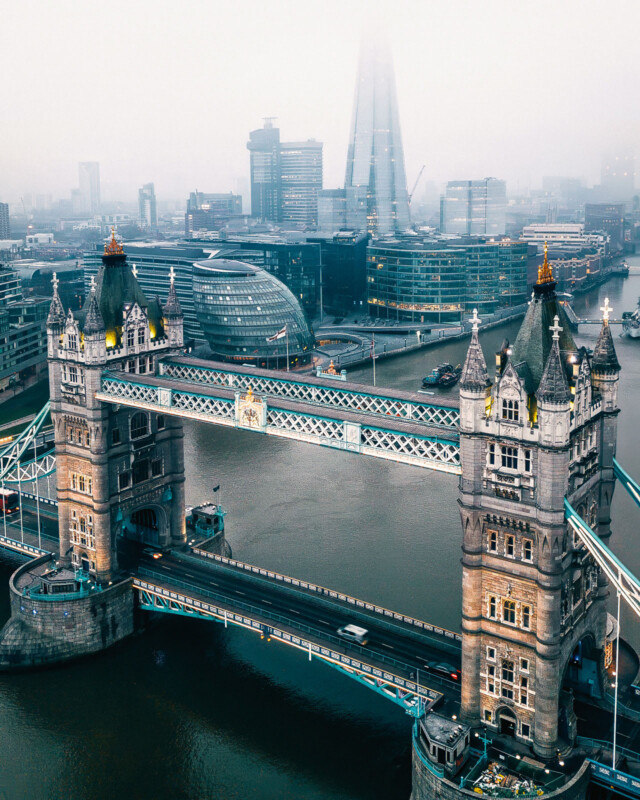 Vista aérea del Puente de la Torre de Londres a través del río Thames, edificios modernos de la ciudad y rascacielos de escombros que se elevan en el fondo.