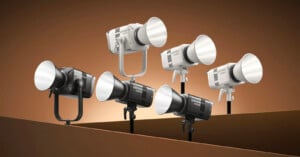 Six studio lights, three black and three white, are displayed against a brown gradient background. Some lights are mounted on stands, while others are positioned on a flat surface.