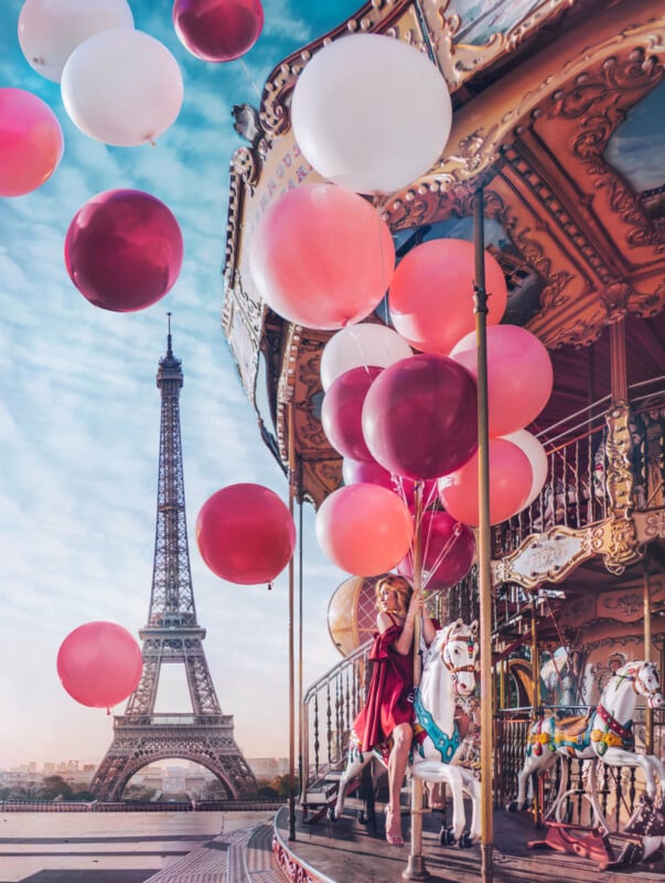 A woman in a red dress sits on a carousel horse holding pink, red, and white balloons, with the Eiffel Tower in the background under a blue sky.