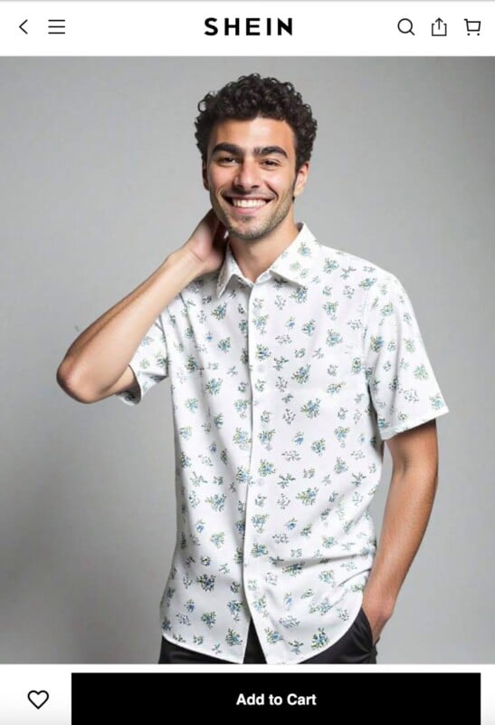 A man with curly hair smiles while wearing a white, short-sleeved, button-up shirt with a small floral print, posing with one hand behind his neck against a plain gray background.