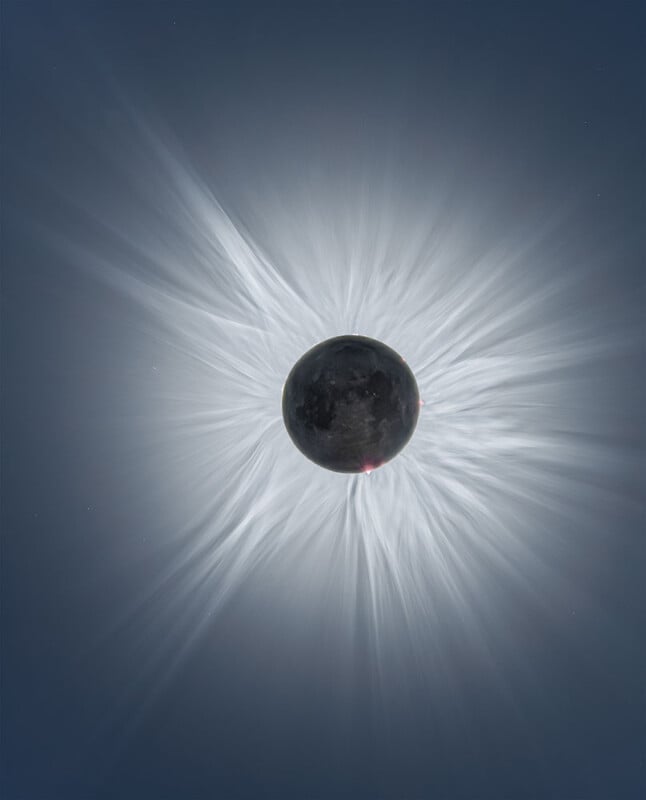 A total solar eclipse showing the dark silhouette of the Moon perfectly aligned with the Sun, with the Sun’s white, wispy corona radiating outward against a dark blue sky.