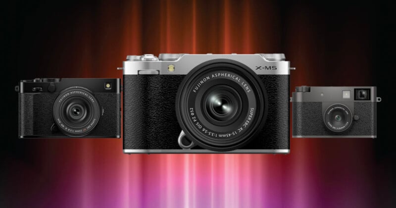 Three digital cameras are displayed side by side against a vibrant, blurred red and purple background, with the central silver and black camera prominently in front.