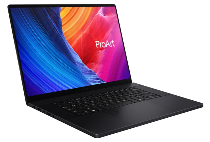 A sleek black laptop with a vivid display showing abstract colorful artwork and the word "ProArt" on the screen, viewed from the front-left angle.