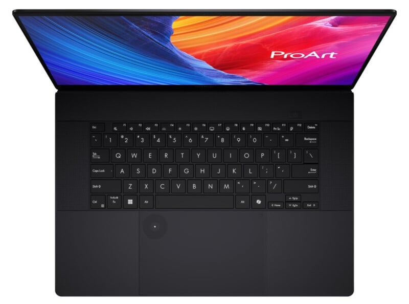 A black laptop viewed from above, showing its keyboard and trackpad. The screen displays colorful abstract art with the word "ProArt" in the top right corner.
