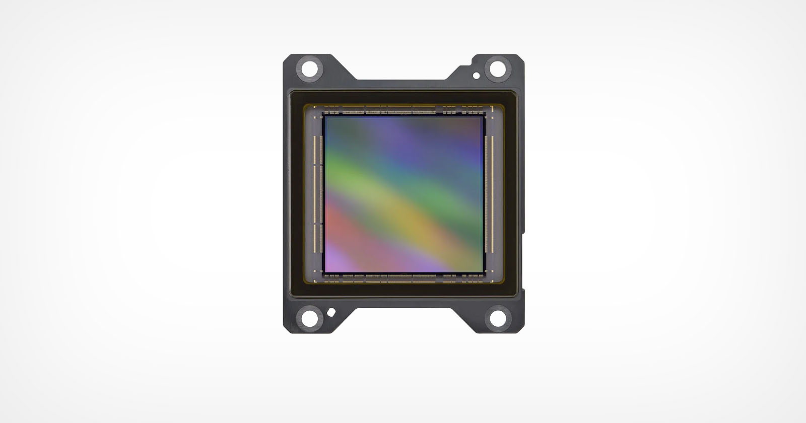 A close-up image of an electronic sensor, likely a camera sensor, with a rainbow-colored reflective surface and four mounting holes, set against a plain white background.