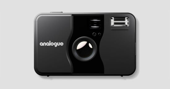 A black analogue film camera with a large lens in the center, a flash in the upper right corner, and the word "analogue" printed in white on the left side. The camera is shown against a plain gray background.