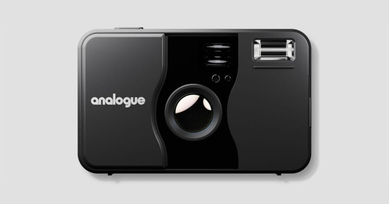 A black analogue film camera with a large lens in the center, a flash in the upper right corner, and the word "analogue" printed in white on the left side. The camera is shown against a plain gray background.