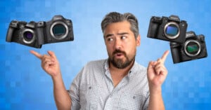 A man with gray hair and a beard stands in front of a blue background, looking thoughtful while pointing at three floating cameras: Canon, Sony, and Nikon.