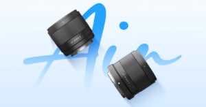 Two black camera lenses are positioned diagonally on a light blue background with the word "Air" written in large, cursive blue letters behind them.
