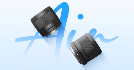 Two black camera lenses are positioned diagonally on a light blue background with the word "Air" written in large, cursive blue letters behind them.