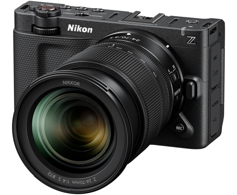 A Nikon Z series digital camera with a large NIKKOR lens is shown at an angle, displaying its textured grip, control dials, and various labeled buttons.