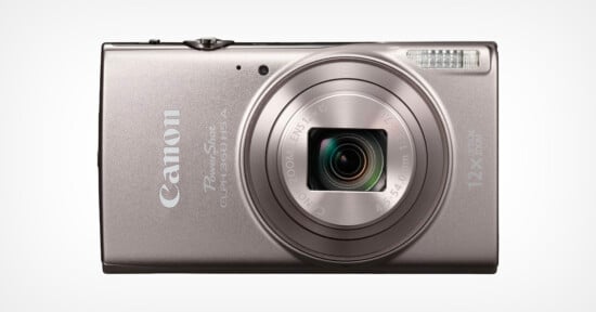 A silver Canon PowerShot digital camera with a retractable lens, flash, and 12x optical zoom, shown facing forward against a plain white background.