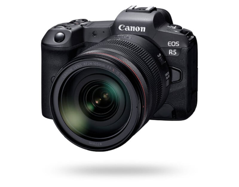 A Canon EOS R5 digital camera with a large lens is shown facing forward on a white background, with a subtle shadow below it.