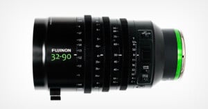 A Fujinon 32-90mm cinema zoom lens with multiple focus, zoom, and aperture rings, displayed horizontally against a white background. The lens features green accents and detailed focal length markings.
