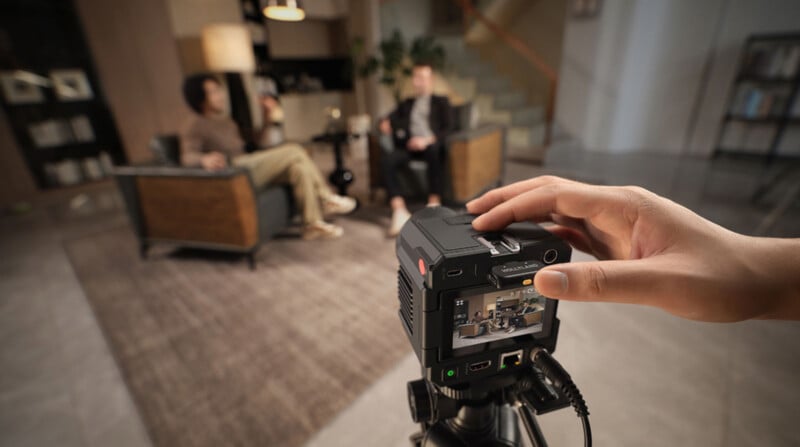 Primer plano de la cámara de dos personas sentadas en sillones en la moderna sala de estar ligera con estantes y escaleras en el fondo.