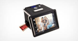 A black HP digital scanner displays a family photo on its screen while scanning a strip of photographic film, with the film partially inserted into the device.