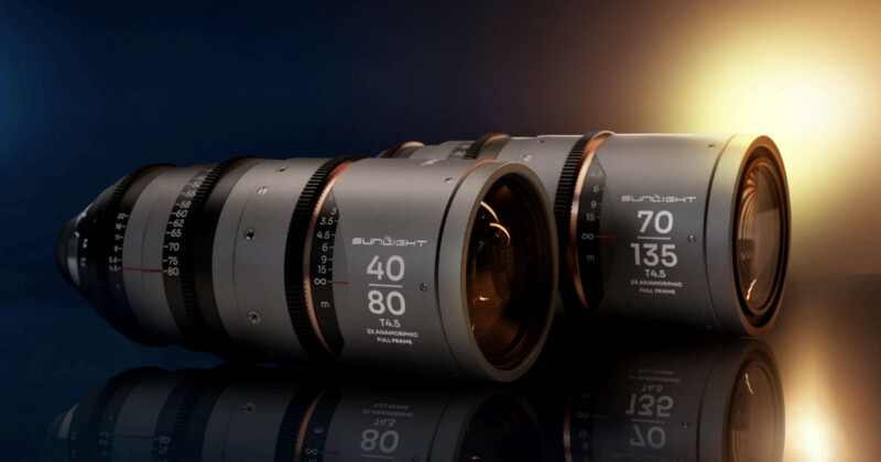 Dos lentes de cámara profesionales con marcas "40-80 mm" y "70-135 mm" Descansa uno al lado del otro en la superficie reflectante, iluminada por una dramática iluminación azul y amarilla en el fondo.