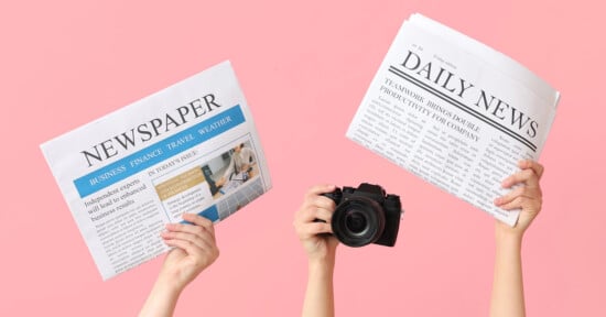 Two hands hold up a newspaper with a blue header and a camera, while two other hands hold a newspaper with a black "DAILY NEWS" header, against a pink background.
