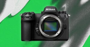 A Nikon Z-series mirrorless camera with no lens attached, showing the sensor, against a green and black abstract background.