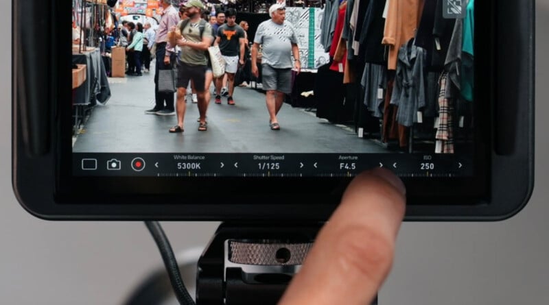 A close-up of a camera screen shows a street market scene with people walking between clothing stalls. A finger is adjusting camera settings, including ISO 250, f/4.5 aperture, and 1/125 shutter speed.