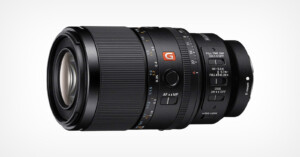 A close-up of a black Sony G Master camera lens with various control switches, focus and zoom rings, and detailed markings, set against a plain white background.